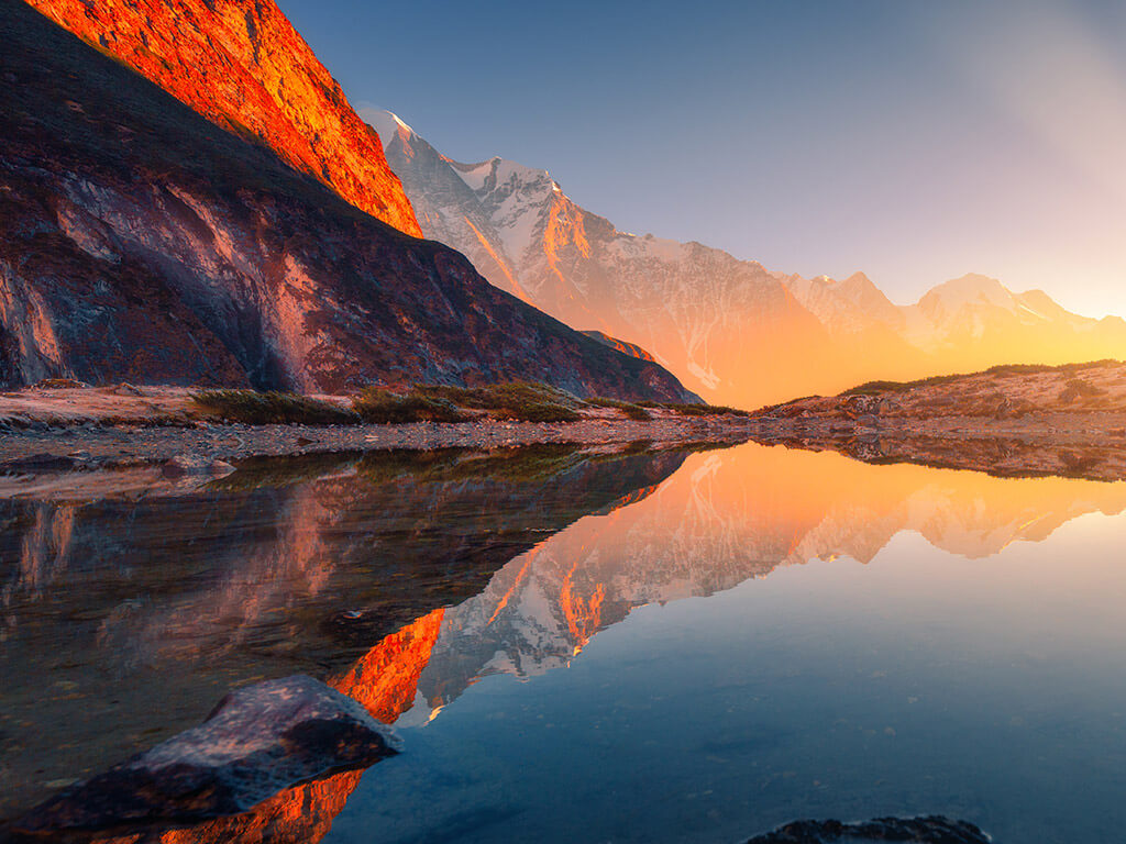 Scenic lake reflecting mountains illuminated by a sunset